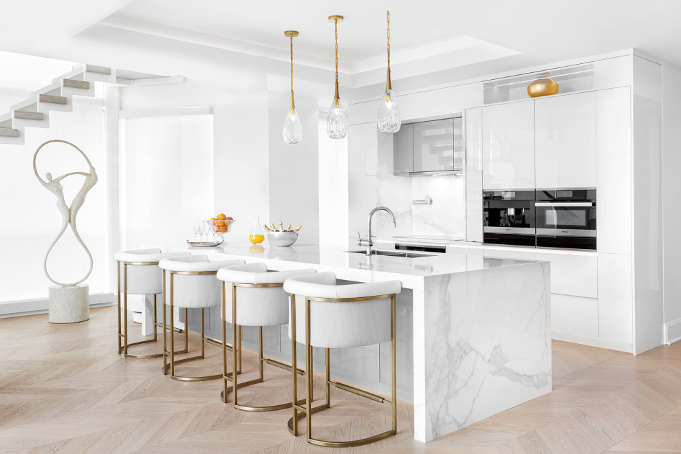 This is an example of a contemporary single-wall kitchen in Montreal with an undermount sink, flat-panel cabinets, white cabinets, marble benchtops, multi-coloured splashback, panelled appliances, light hardwood floors, with island, beige floor, multi-coloured benchtop and recessed.