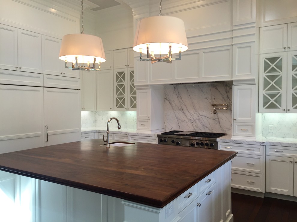 This is an example of an expansive transitional u-shaped open plan kitchen in San Diego with a farmhouse sink, recessed-panel cabinets, white cabinets, wood benchtops, white splashback, marble splashback, stainless steel appliances, with island and brown benchtop.