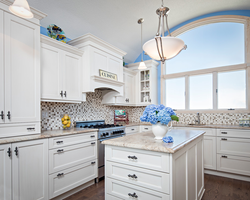 This is an example of a mid-sized beach style u-shaped eat-in kitchen in New York with an undermount sink, white cabinets, with island, multi-coloured splashback, shaker cabinets, limestone benchtops, mosaic tile splashback, stainless steel appliances and dark hardwood floors.