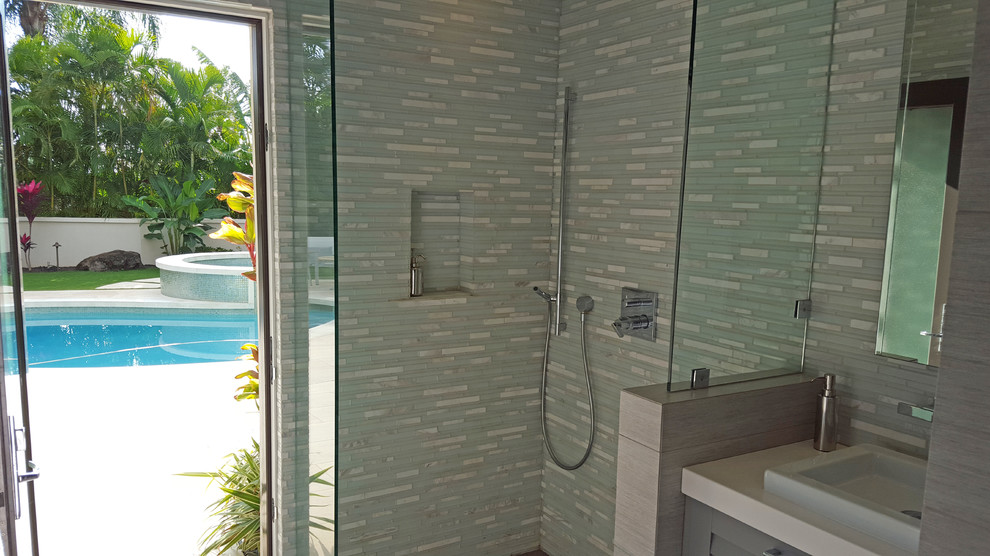 Photo of a mid-sized tropical 3/4 bathroom in Other with louvered cabinets, grey cabinets, a corner shower, blue tile, white tile, matchstick tile, multi-coloured walls, porcelain floors, a vessel sink and quartzite benchtops.