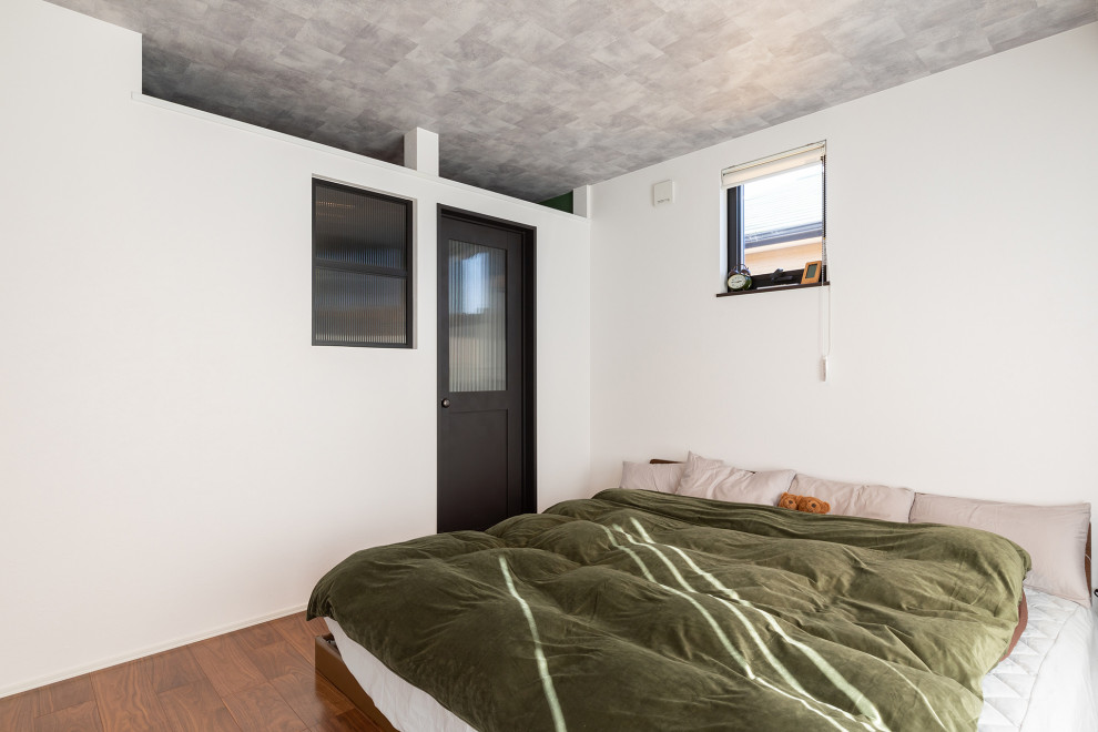 Ejemplo de dormitorio principal y gris con paredes blancas y suelo marrón