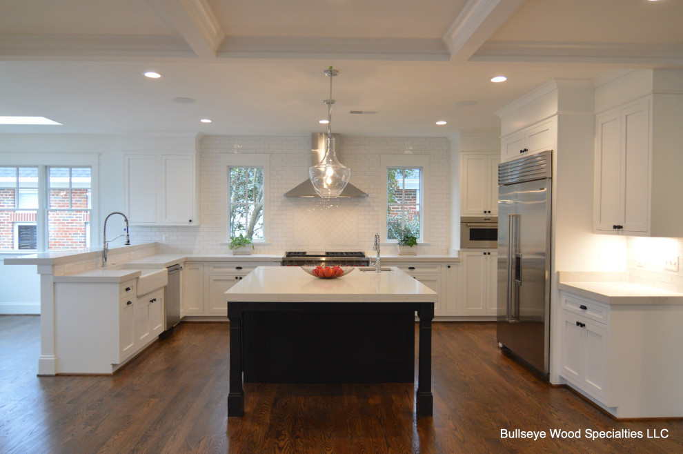 Photo of a large transitional u-shaped eat-in kitchen in DC Metro with a farmhouse sink, shaker cabinets, white cabinets, quartz benchtops, white splashback, subway tile splashback, stainless steel appliances, medium hardwood floors, with island, brown floor and white benchtop.