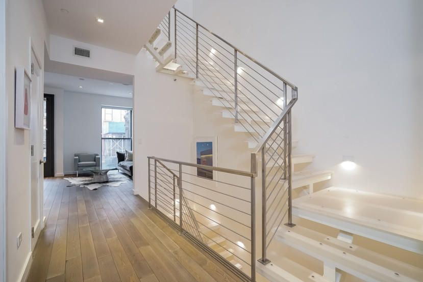 Mid-sized contemporary glass l-shaped staircase in New York with open risers and metal railing.