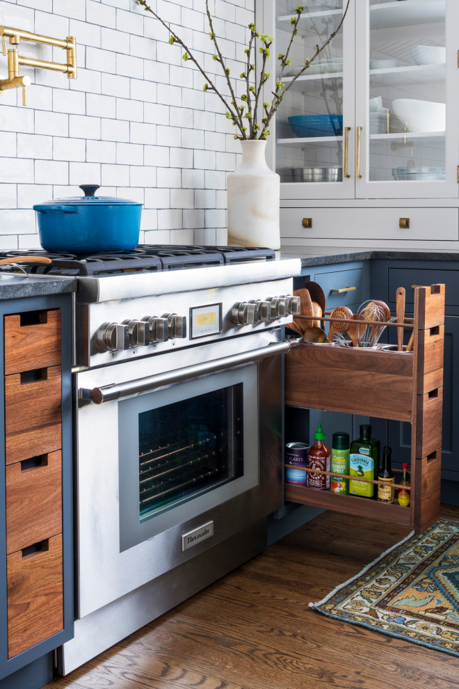 Klassisk inredning av ett mellanstort svart svart u-kök, med en enkel diskho, skåp i shakerstil, blå skåp, granitbänkskiva, vitt stänkskydd, stänkskydd i keramik, integrerade vitvaror, mellanmörkt trägolv, en köksö och brunt golv