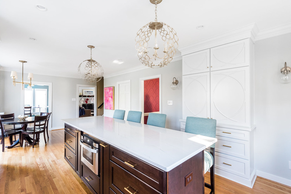 Example of a transitional medium tone wood floor kitchen design in Richmond with a farmhouse sink, shaker cabinets, white cabinets, quartzite countertops, white backsplash, subway tile backsplash, stainless steel appliances and an island