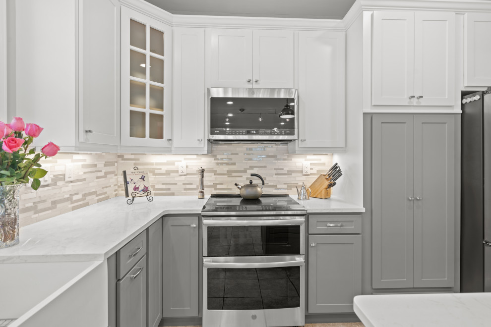 Modern inredning av ett stort vit vitt kök, med en rustik diskho, släta luckor, grå skåp, bänkskiva i kvarts, grått stänkskydd, stänkskydd i mosaik, rostfria vitvaror, klinkergolv i porslin, en köksö och beiget golv
