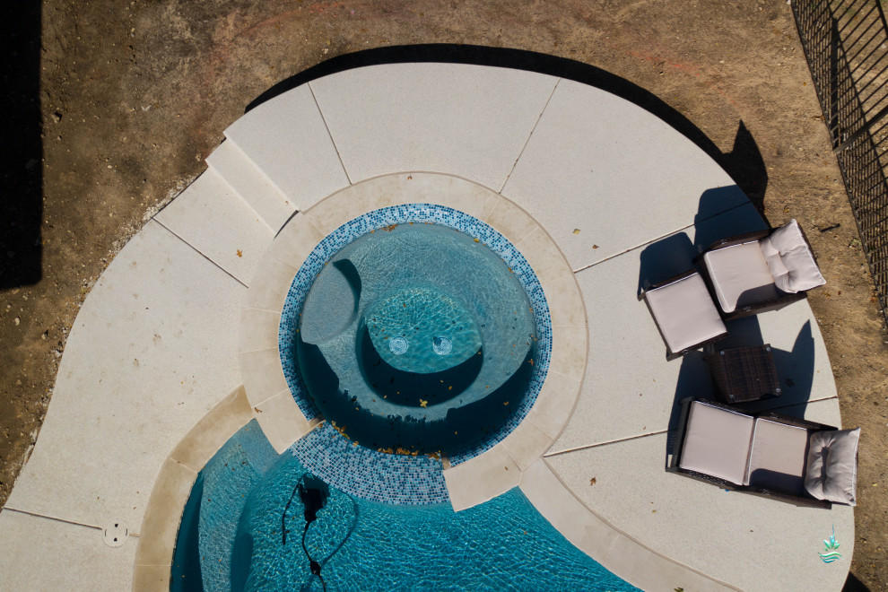 Foto di una grande piscina naturale mediterranea personalizzata dietro casa con una vasca idromassaggio e lastre di cemento