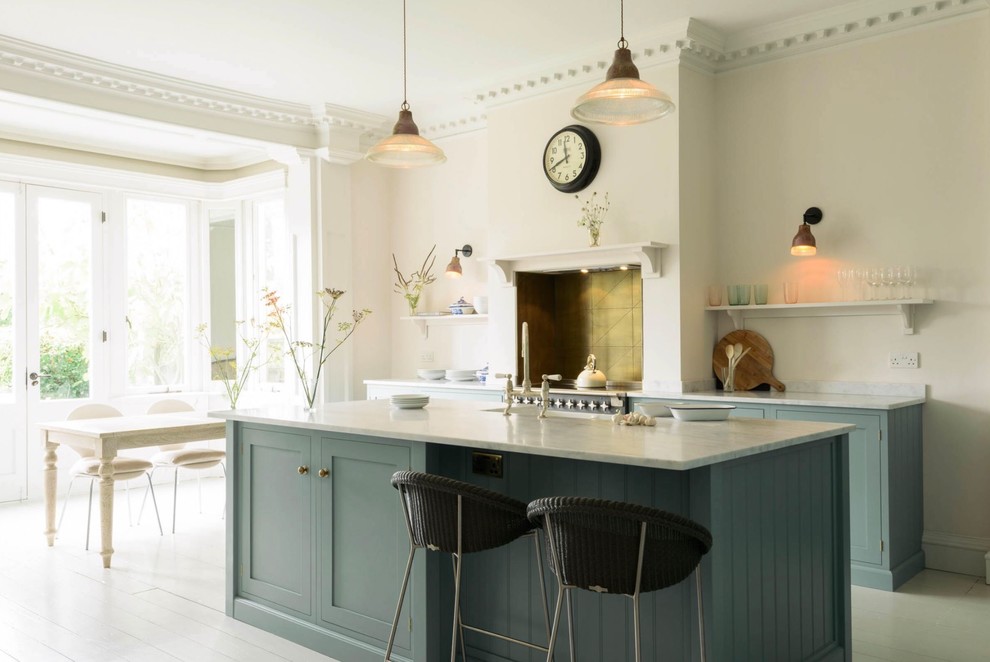 Design ideas for a transitional galley eat-in kitchen in Hertfordshire with a farmhouse sink, shaker cabinets, blue cabinets, marble benchtops, metal splashback, stainless steel appliances, painted wood floors, with island and grey benchtop.