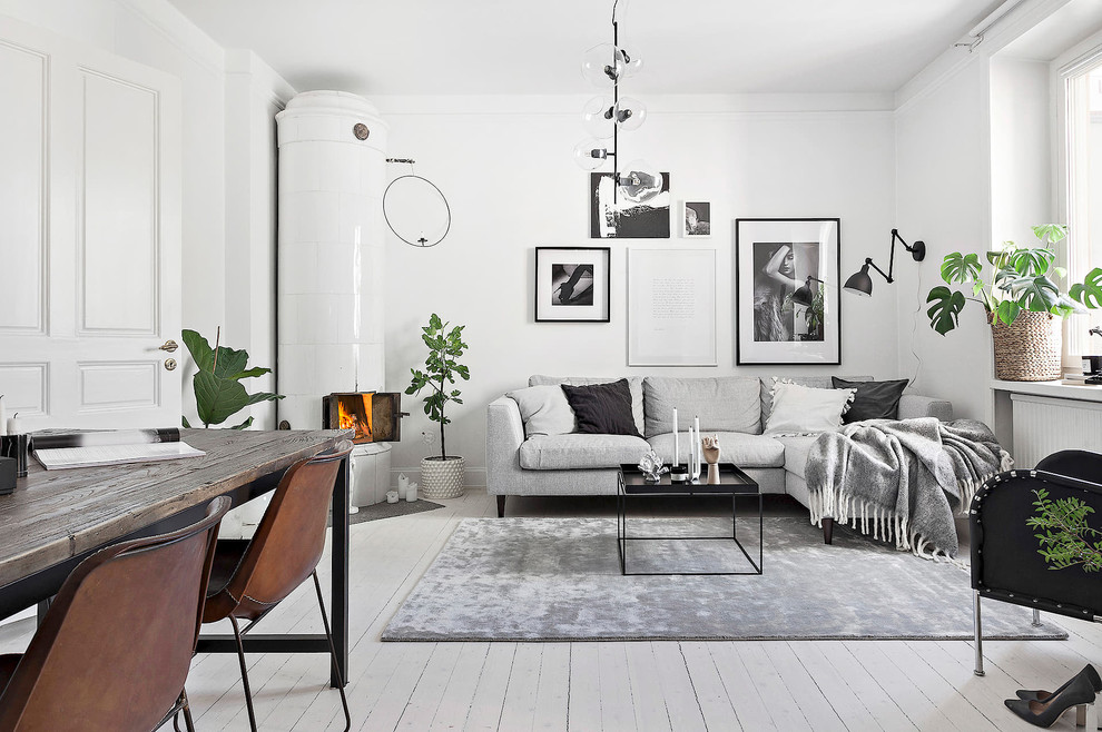 Design ideas for a scandinavian living room in Stockholm with white walls, painted wood floors, a corner fireplace, a tile fireplace surround and white floor.