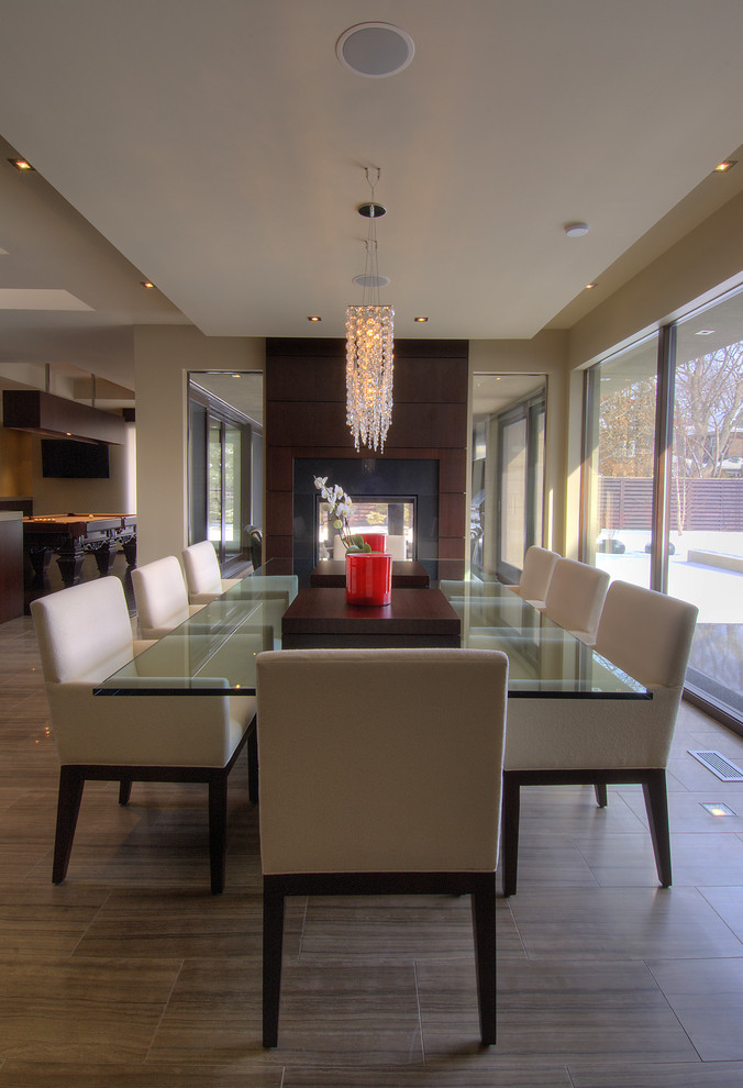 This is an example of a large contemporary kitchen/dining combo in Toronto with beige walls, porcelain floors, a two-sided fireplace, a stone fireplace surround and brown floor.