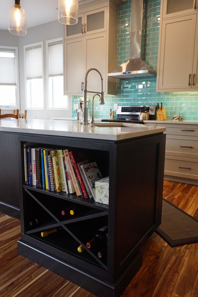 Example of a mid-sized transitional l-shaped medium tone wood floor and brown floor kitchen design in Calgary with an undermount sink, shaker cabinets, gray cabinets, quartz countertops, blue backsplash, ceramic backsplash, stainless steel appliances and an island