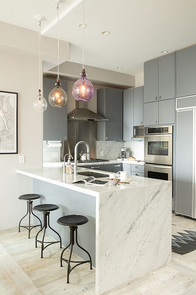 Photo of a contemporary u-shaped kitchen in San Francisco with an undermount sink, flat-panel cabinets, grey cabinets, white splashback, stainless steel appliances, light hardwood floors and a peninsula.