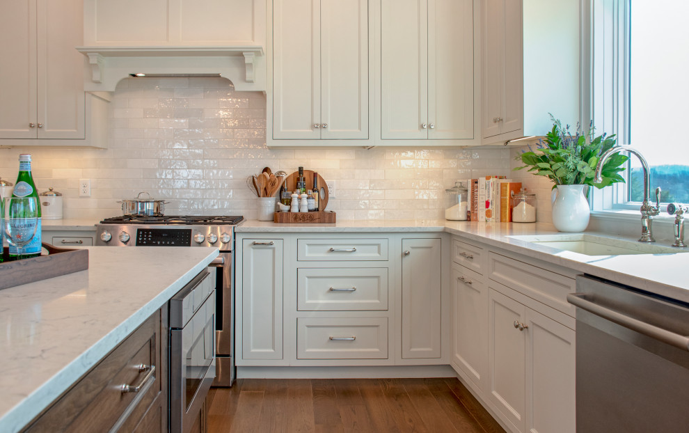 Inspiration for a transitional medium tone wood floor and brown floor eat-in kitchen remodel with an undermount sink, shaker cabinets, white cabinets, quartz countertops, white backsplash, ceramic backsplash, stainless steel appliances, an island and white countertops