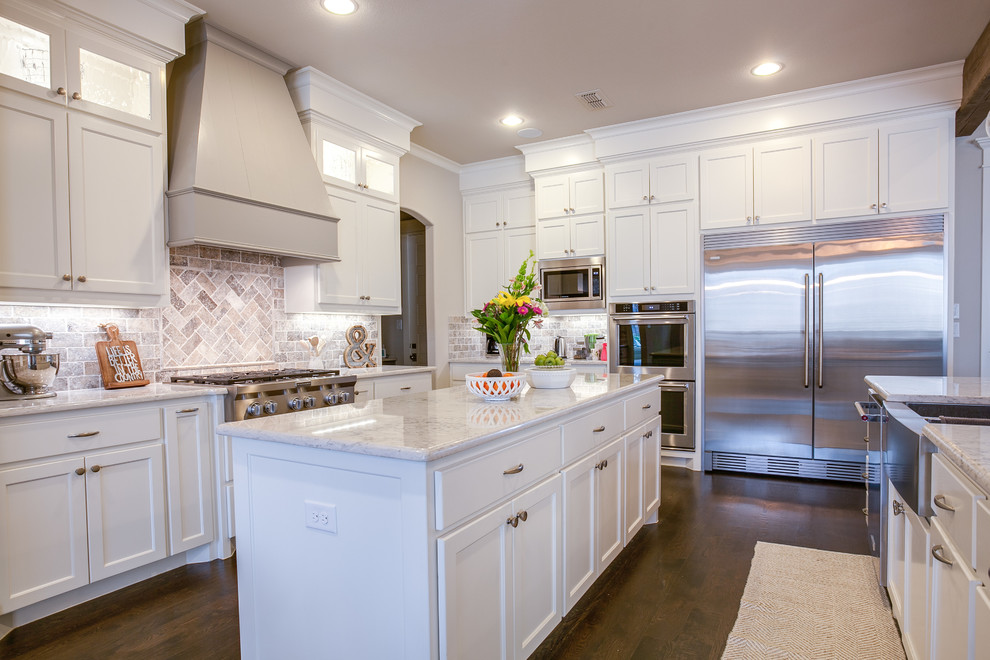 Large contemporary u-shaped open plan kitchen in Dallas with shaker cabinets, white cabinets, marble benchtops, grey splashback, stone tile splashback, stainless steel appliances, dark hardwood floors, multiple islands, a farmhouse sink and brown floor.