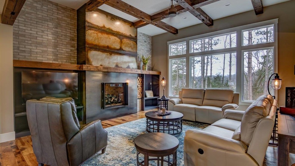 Inspiration for a country living room in Minneapolis with beige walls, medium hardwood floors, a standard fireplace, a metal fireplace surround, a wall-mounted tv and brown floor.