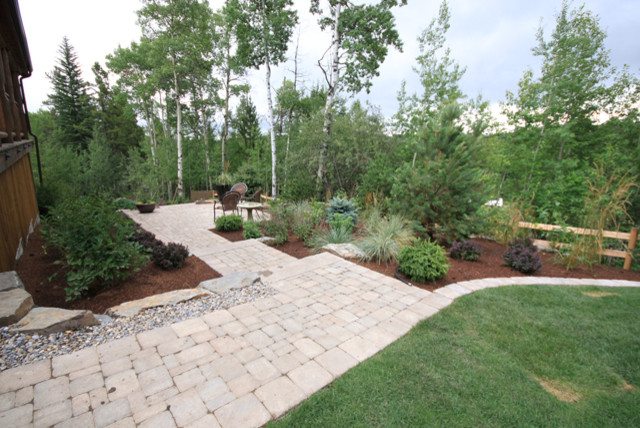 Photo of a huge traditional partial sun backyard concrete paver garden path in Calgary for summer.
