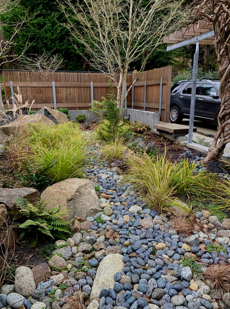 Small modern courtyard partial sun xeriscape in Seattle with with rock feature and river rock for winter.