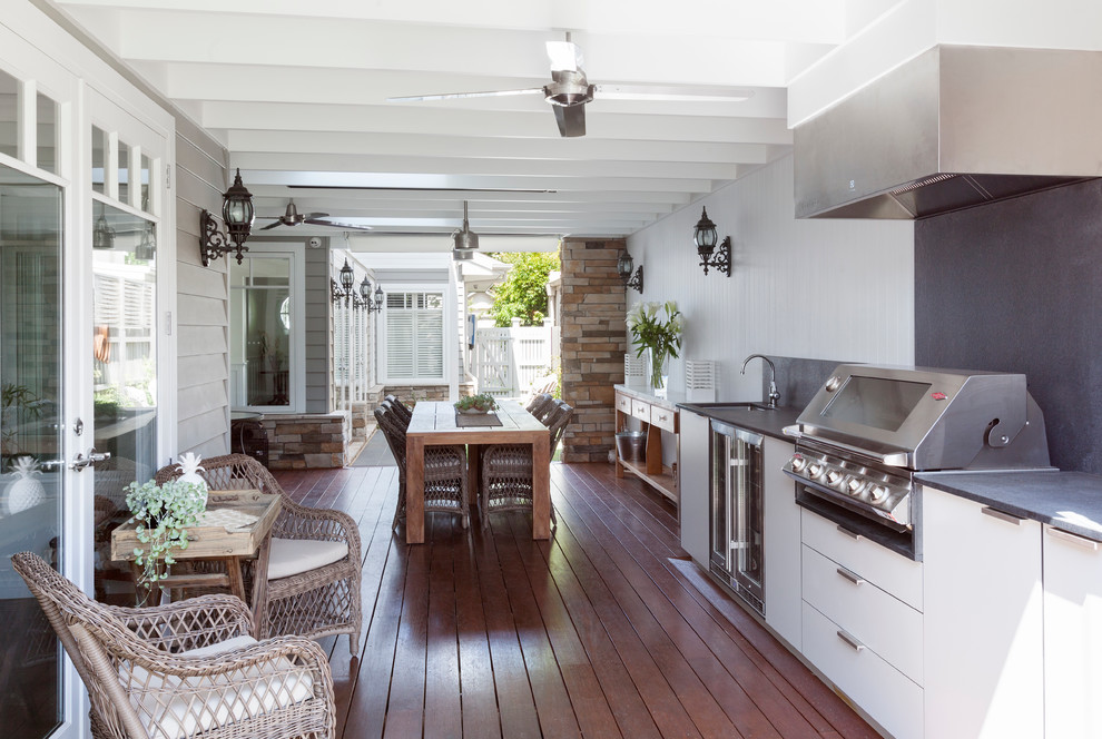 Large transitional backyard deck in Melbourne with an outdoor kitchen and a roof extension.