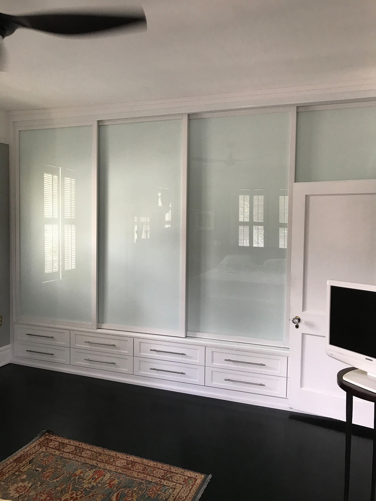 Inspiration for a small contemporary gender-neutral built-in wardrobe in Jacksonville with shaker cabinets, white cabinets, laminate floors and black floor.