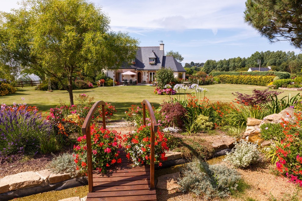 Imagen de jardín clásico extra grande en patio delantero con exposición total al sol, fuente y jardín francés