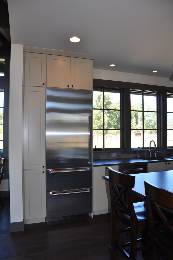 Inspiration for a large rustic l-shaped medium tone wood floor eat-in kitchen remodel in Seattle with an undermount sink, shaker cabinets, distressed cabinets, quartz countertops, gray backsplash, stone tile backsplash, stainless steel appliances and an island