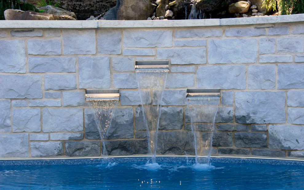 Example of a mid-sized classic backyard concrete paver and custom-shaped pool fountain design in Montreal