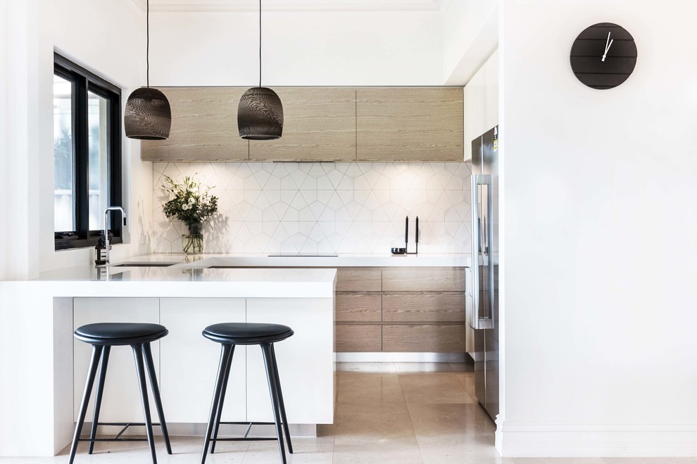 Mid-sized contemporary u-shaped eat-in kitchen in Perth with a double-bowl sink, flat-panel cabinets, light wood cabinets, quartz benchtops, white splashback, ceramic splashback, black appliances, limestone floors and with island.