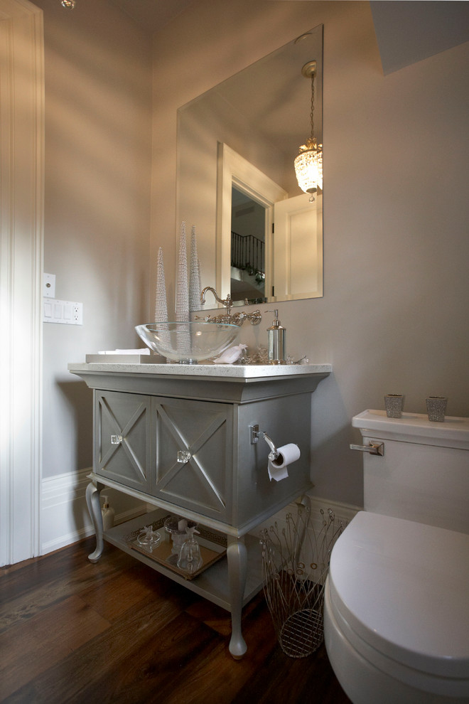 This is an example of a mid-sized traditional powder room in Toronto with furniture-like cabinets, grey cabinets, grey walls, medium hardwood floors and a vessel sink.