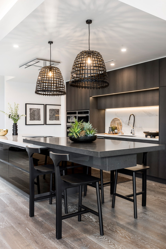 Design ideas for a contemporary galley kitchen in Gold Coast - Tweed with an undermount sink, flat-panel cabinets, black cabinets, white splashback, medium hardwood floors, with island, brown floor and white benchtop.