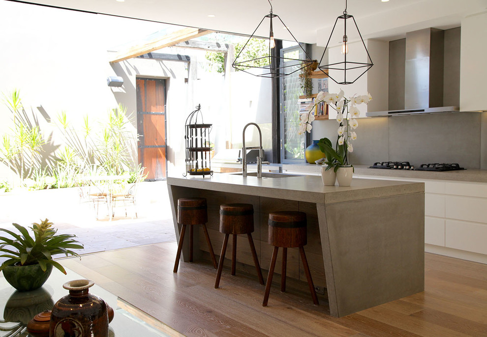 Photo of a contemporary l-shaped kitchen in Sydney with an undermount sink, concrete benchtops, grey splashback, stainless steel appliances, light hardwood floors and with island.