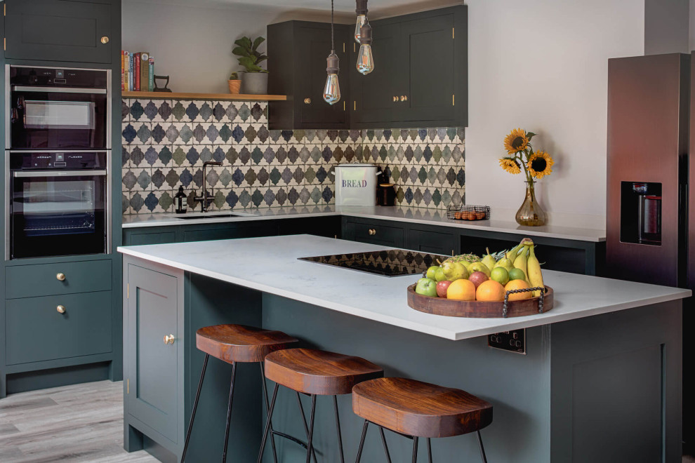 Inspiration for a mid-sized transitional l-shaped eat-in kitchen in Other with shaker cabinets, green cabinets, quartzite benchtops, green splashback, ceramic splashback, laminate floors, with island, white benchtop, an undermount sink, black appliances and grey floor.