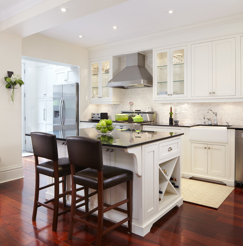 Inspiration for a mid-sized traditional single-wall eat-in kitchen in Toronto with a farmhouse sink, shaker cabinets, white cabinets, white splashback, mosaic tile splashback, stainless steel appliances, dark hardwood floors, with island and granite benchtops.