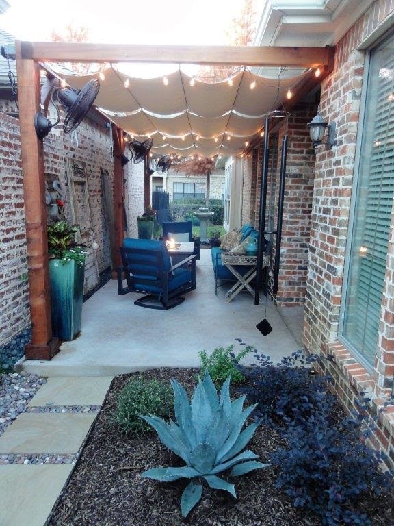 Photo of a small transitional side yard patio in Dallas with a fire feature, concrete pavers and an awning.