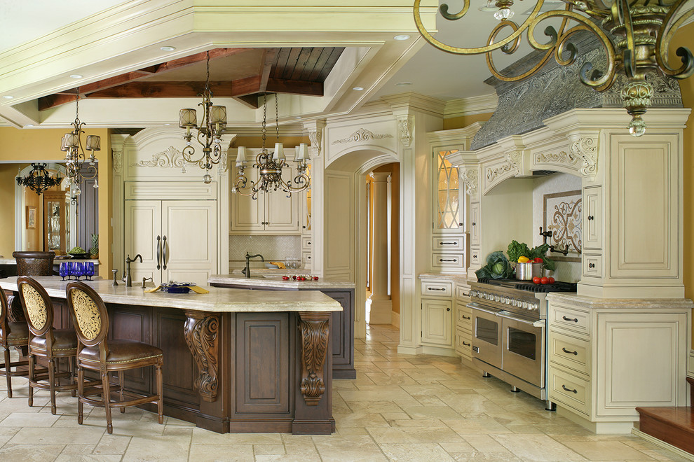 This is an example of a large traditional l-shaped eat-in kitchen in New York with a farmhouse sink, beaded inset cabinets, white cabinets, limestone benchtops, beige splashback, stone tile splashback, panelled appliances, travertine floors and multiple islands.