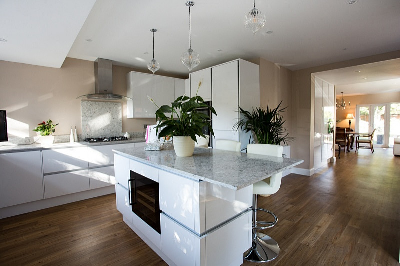 Example of a trendy u-shaped kitchen design in Sussex with an undermount sink, glass-front cabinets, white cabinets, quartzite countertops, gray backsplash, quartz backsplash, paneled appliances, an island and gray countertops