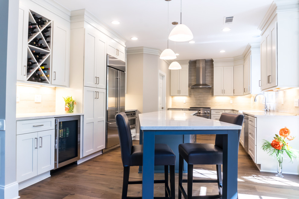Inspiration for a large transitional u-shaped dark wood floor and brown floor enclosed kitchen remodel in Atlanta with a farmhouse sink, shaker cabinets, white cabinets, stainless steel appliances, an island, white countertops, beige backsplash, quartz countertops and cement tile backsplash