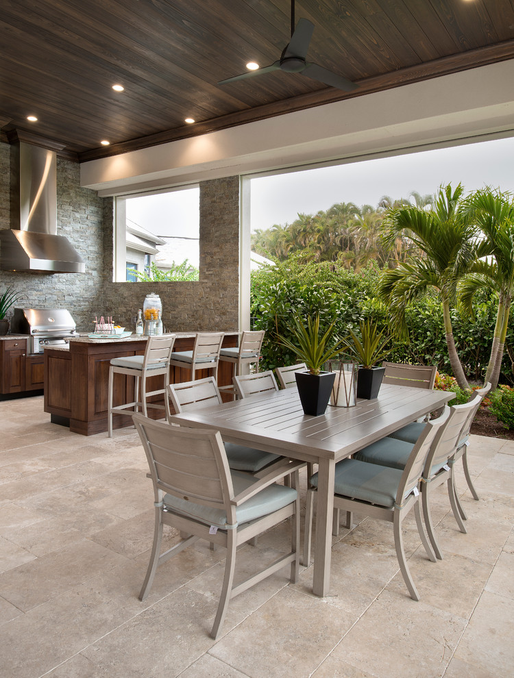 Photo of an expansive transitional backyard patio in Tampa with an outdoor kitchen, natural stone pavers and a roof extension.