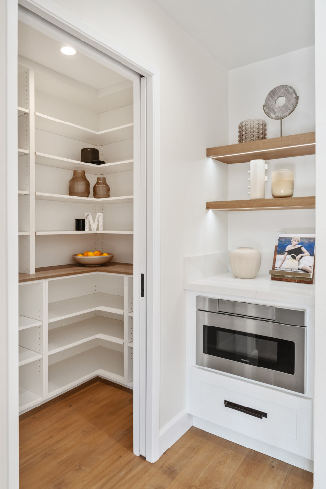 Mid-sized transitional vinyl floor and brown floor open concept kitchen photo in Orange County with an undermount sink, shaker cabinets, white cabinets, quartz countertops, white backsplash, quartz backsplash, stainless steel appliances, an island and white countertops
