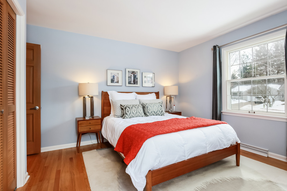 Aménagement d'une chambre parentale blanche et bois rétro de taille moyenne avec un mur bleu, un sol en bois brun, aucune cheminée et un sol marron.