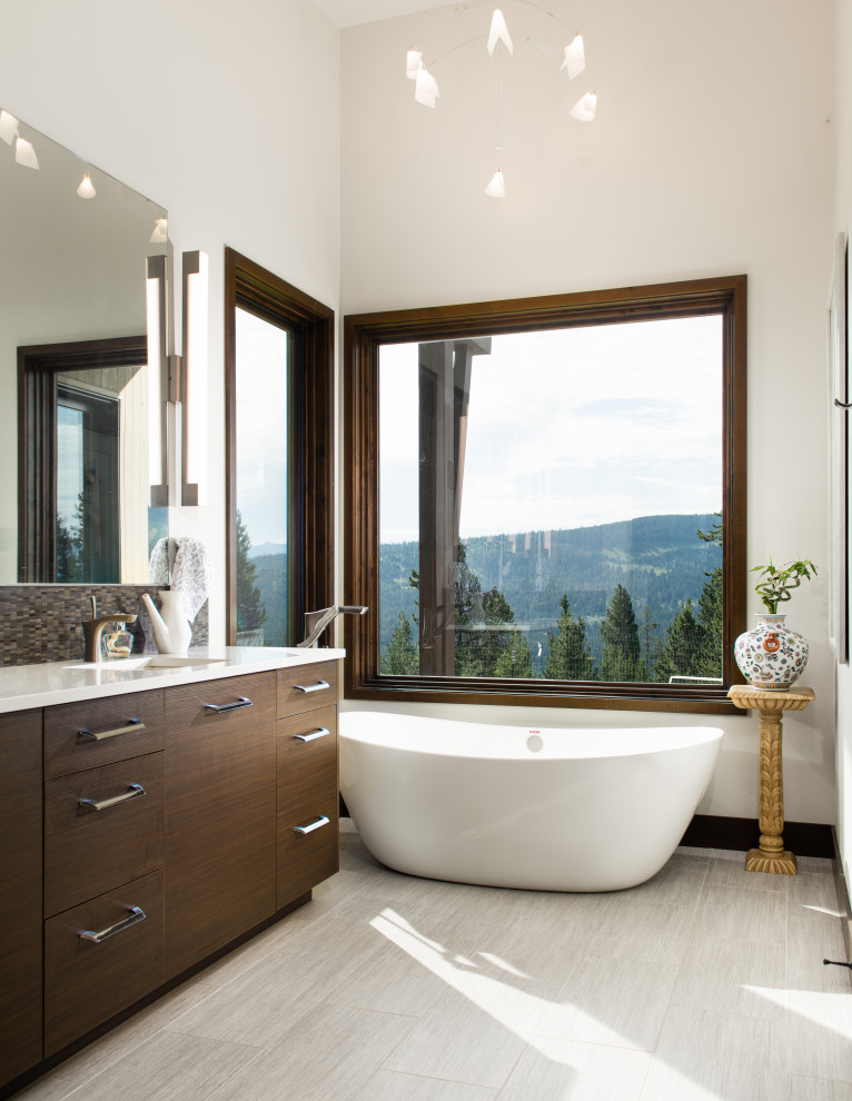 Large rustic ensuite bathroom in Other with flat-panel cabinets, dark wood cabinets, a freestanding bath, white walls, light hardwood flooring, a submerged sink, white worktops, a single sink and a built in vanity unit.