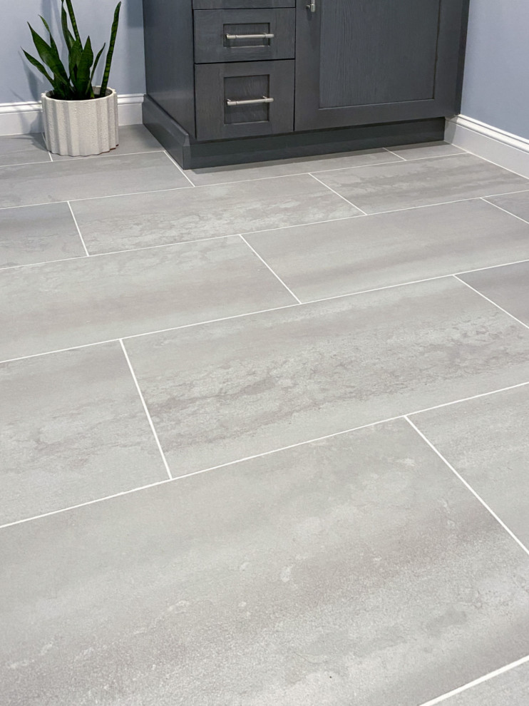 Corner shower - transitional white tile and ceramic tile porcelain tile, gray floor and single-sink corner shower idea in Boston with shaker cabinets, gray cabinets, a one-piece toilet, gray walls, an undermount sink, quartz countertops, a hinged shower door, white countertops and a built-in vanity