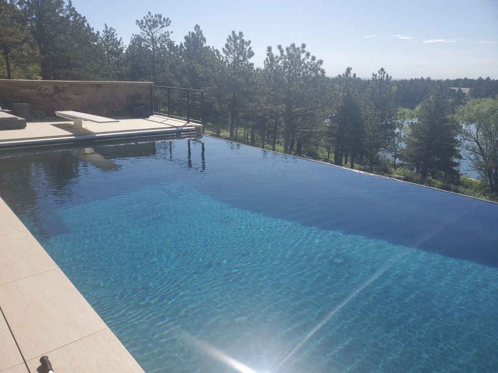 Inspiration for a mid-sized backyard rectangular infinity hot tub remodel in Denver