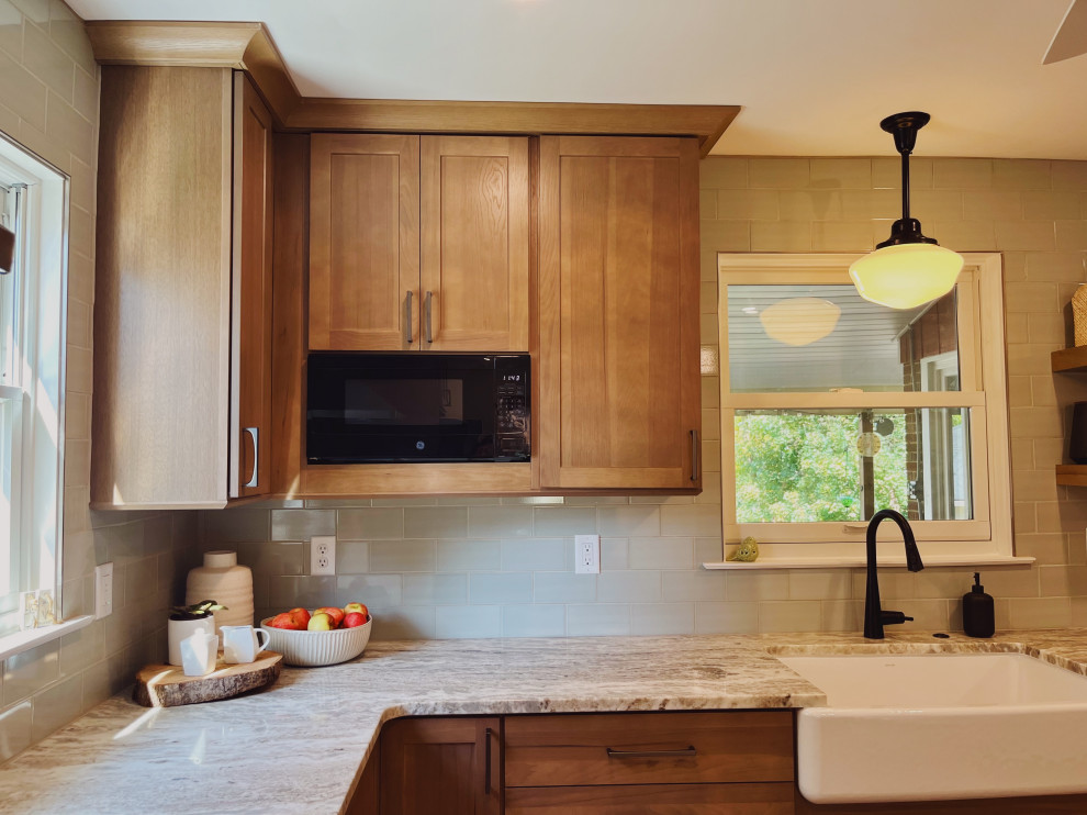 Inspiration for a mid-sized transitional l-shaped vinyl floor and beige floor eat-in kitchen remodel with a farmhouse sink, shaker cabinets, medium tone wood cabinets, quartzite countertops, green backsplash, ceramic backsplash, stainless steel appliances, no island and beige countertops