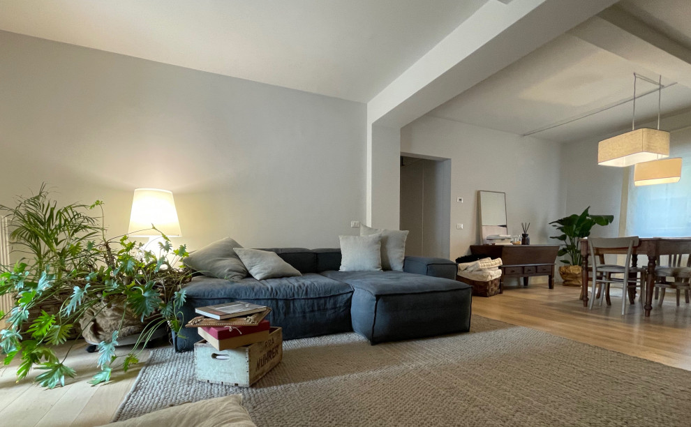 Imagen de sala de estar abierta moderna de tamaño medio con paredes grises, suelo beige, vigas vistas, alfombra, suelo de madera en tonos medios y pared multimedia