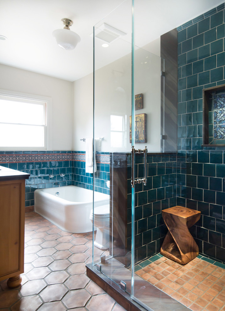 This is an example of a mid-sized mediterranean master bathroom in Los Angeles with an undermount sink, shaker cabinets, medium wood cabinets, quartzite benchtops, a corner tub, a corner shower, a one-piece toilet, blue tile, ceramic tile, white walls and terra-cotta floors.