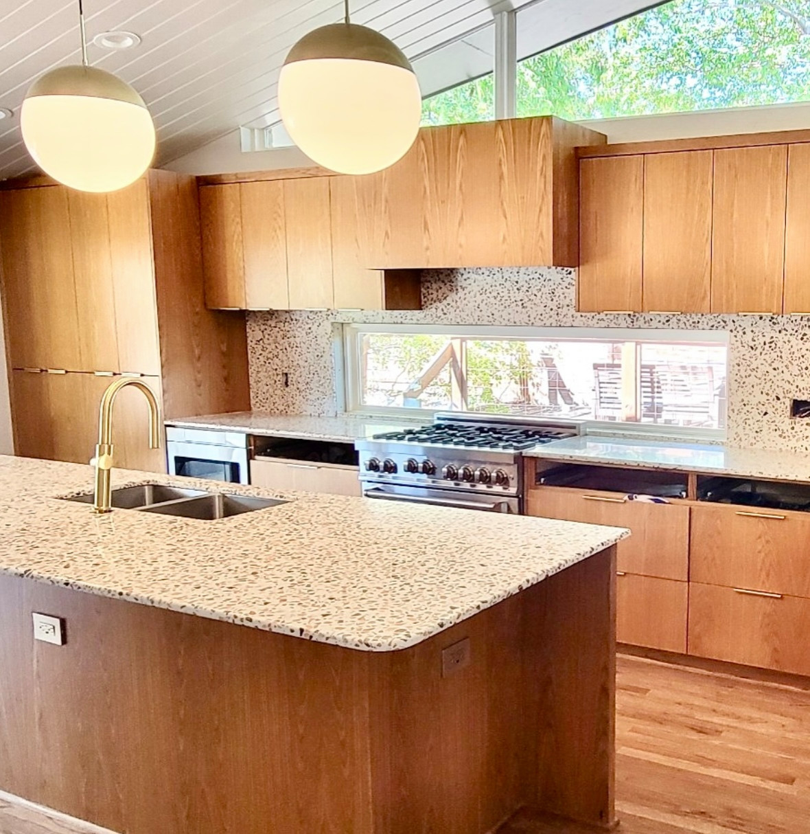 Terrazzo countertops, white oak cabinets, white oak flooring, custom windows, wedge windows, mid century modern, open living space, cathedral ceiling, wood ceiling wood plank ceiling.