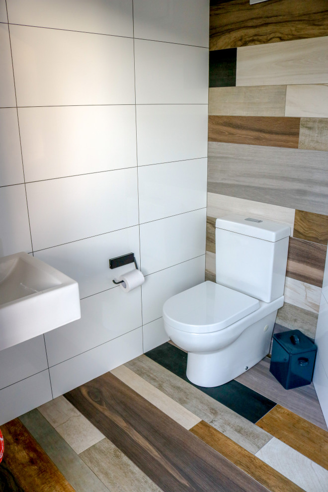 Photo of a small contemporary powder room in Sydney with a one-piece toilet, white tile, ceramic tile, porcelain floors and a wall-mount sink.