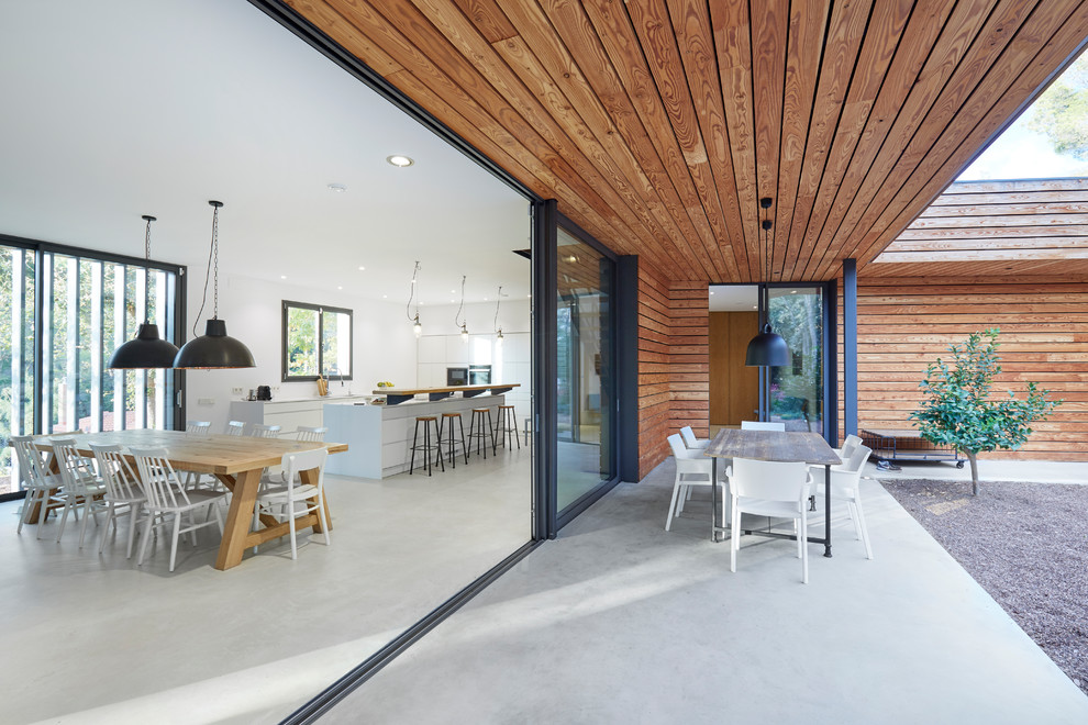 This is an example of a contemporary verandah in Other with concrete slab and a roof extension.