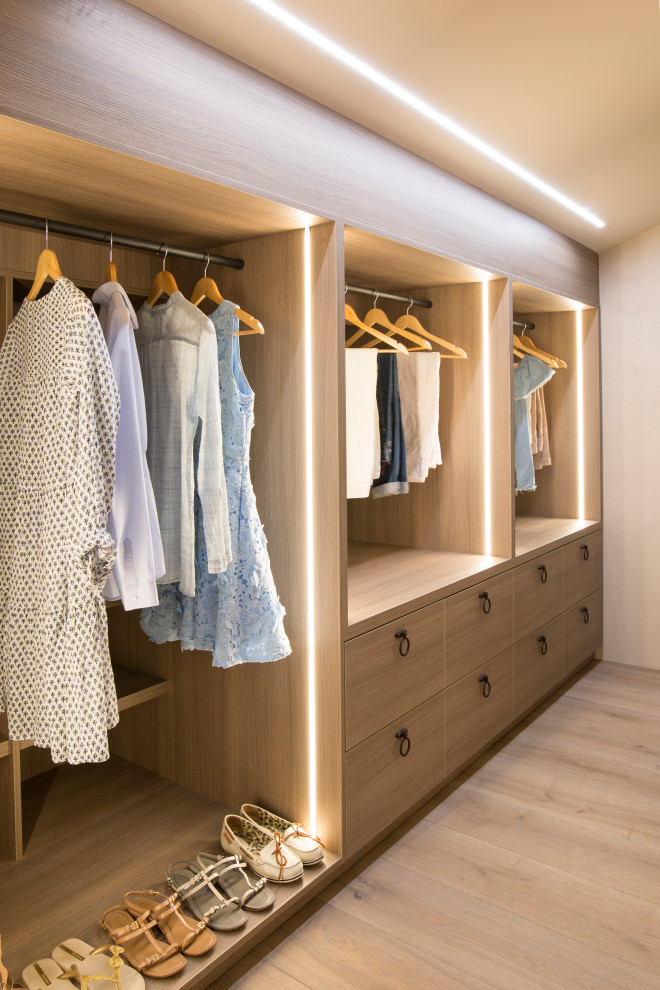 Inspiration for a mediterranean women's storage and wardrobe in Nice with flat-panel cabinets, medium wood cabinets, light hardwood floors, beige floor and vaulted.