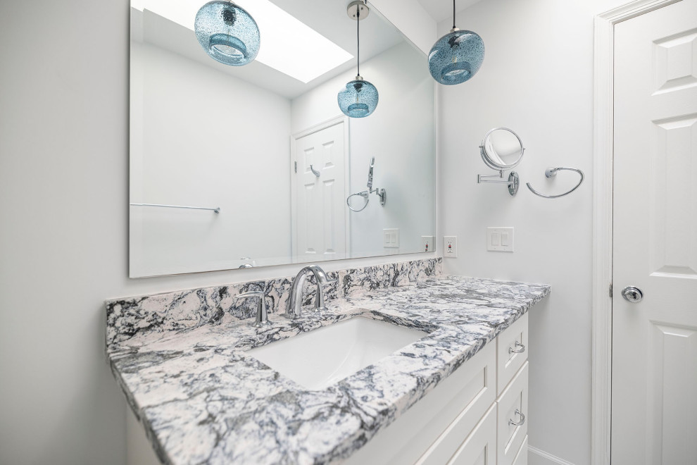 Photo of a mid-sized transitional bathroom in DC Metro with shaker cabinets, white cabinets, an alcove tub, a shower/bathtub combo, white tile, porcelain tile, porcelain floors, an undermount sink, engineered quartz benchtops, white floor, a sliding shower screen, multi-coloured benchtops, a single vanity and a built-in vanity.